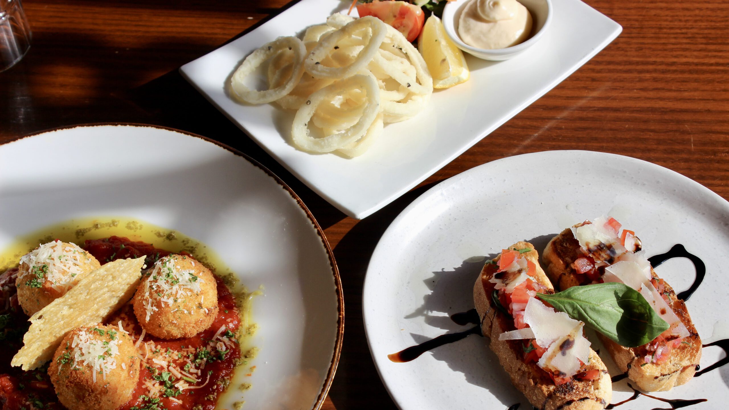 A spread of sharing plates featuring savory meatballs in sauce and fresh bruschetta topped with tomatoes and basil, offering a variety of flavors at Table 48.